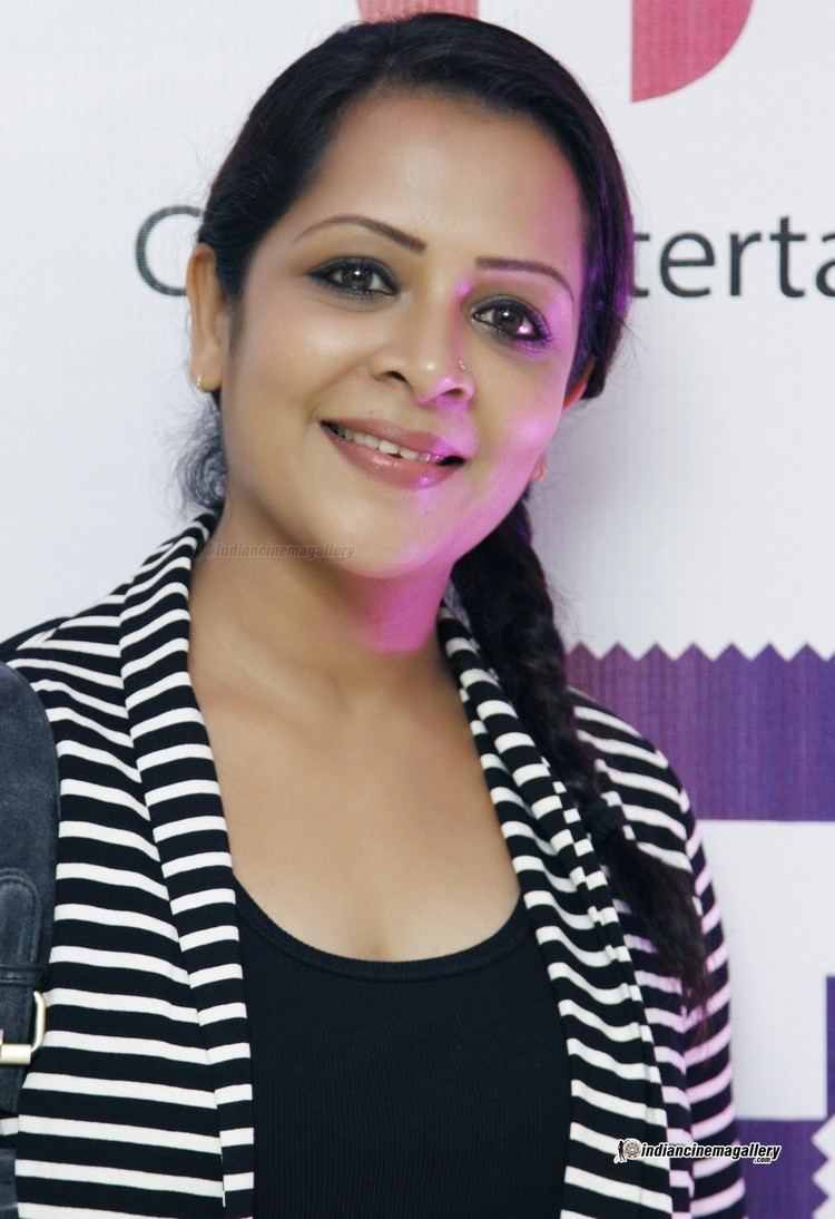 Devi Ajith smiling with her braided hair and wearing a black and white blouse