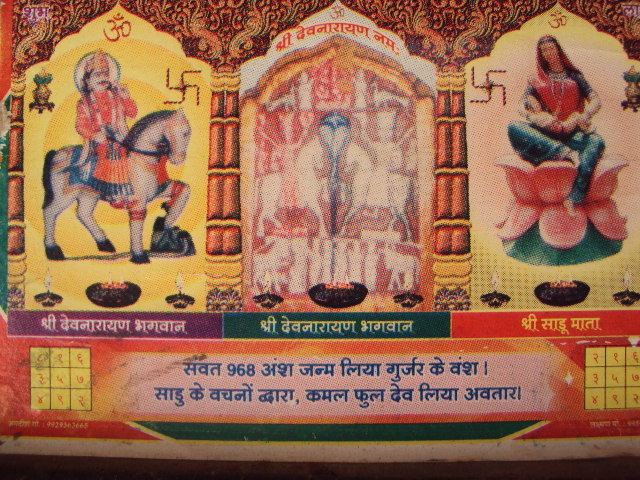 Devnarayan depicted in a calendar alongside Saadu Maata Gurjari riding a horse with Swastika symbols.