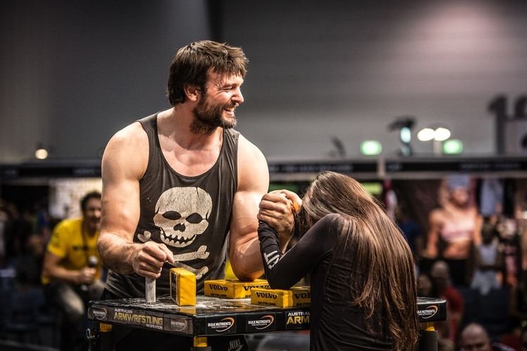 Devon Larratt smiling while on a arm wrestling fight with a woman