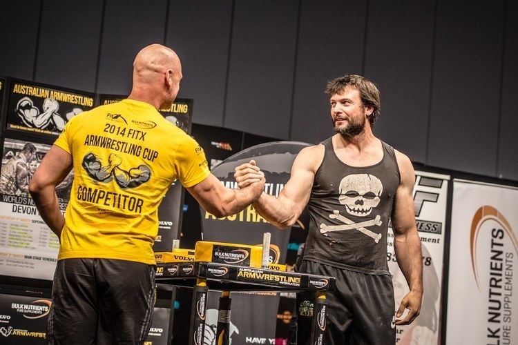 Devon Larratt on a arm wrestling fight while wearing black printed sando