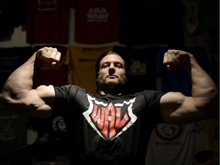 Devon Larratt showing his muscle while wearing black printed shirt