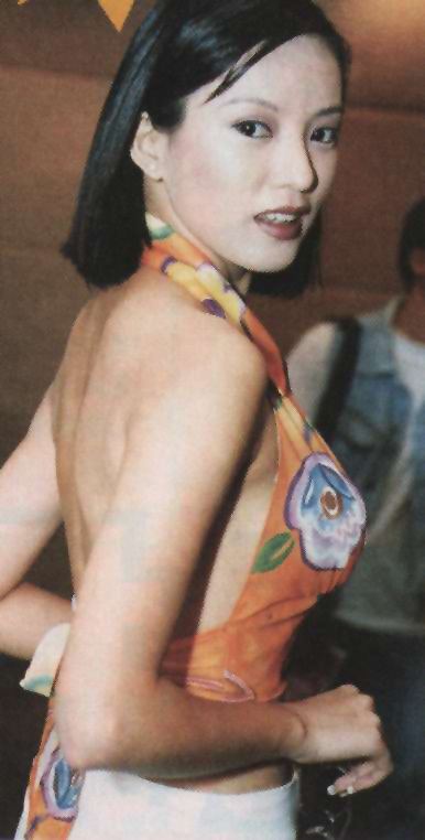 Diana Pang posing while wearing an orange backless floral dress during an event.