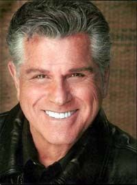 Dick Gautier smiling, with gray hair and wearing a black leather jacket over a black polo shirt.