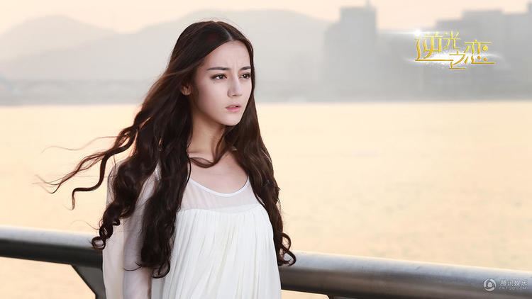 Dilraba Dilmurat looking afar at the seaside while wearing a white blouse