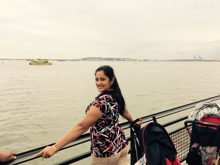 Dini Daniel on a leisurely pose overlooking a river wearing multi-colored clothing beside strollers.