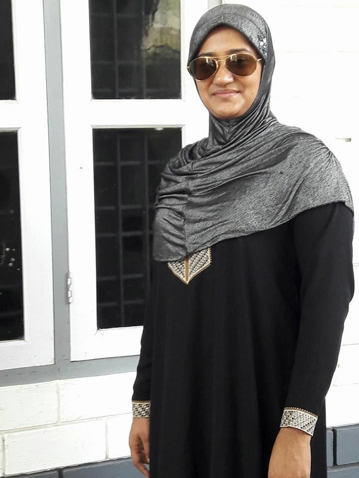 Dini Daniel wearing a gray hijab along with a black dress and sunglasses.