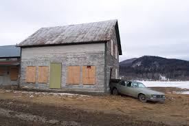 An Oldsmobile Custom Cruiser standing in front of a small wooden house with snow in the background.