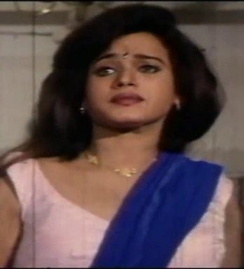 Disco Shanti looking afar while wearing a pink sleeveless dress, blue dupatta, and some pieces of jewelry