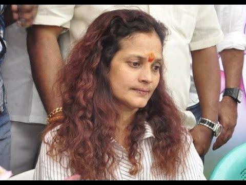 Disco Shanti with curly hair while wearing a black and white striped blouse