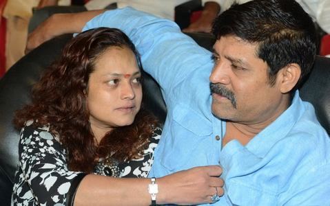 Disco Shanti sitting next to a man wearing blue long sleeves while she is wearing a black and white blouse