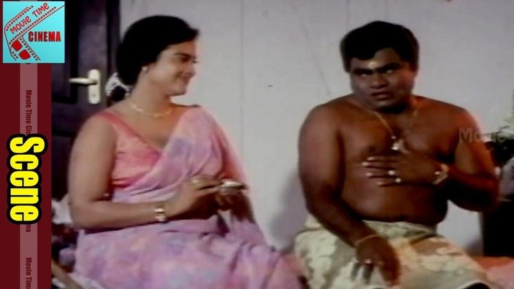 Disco Shanti smiling and wearing a pink dress while the man beside her is wearing a beige skirt