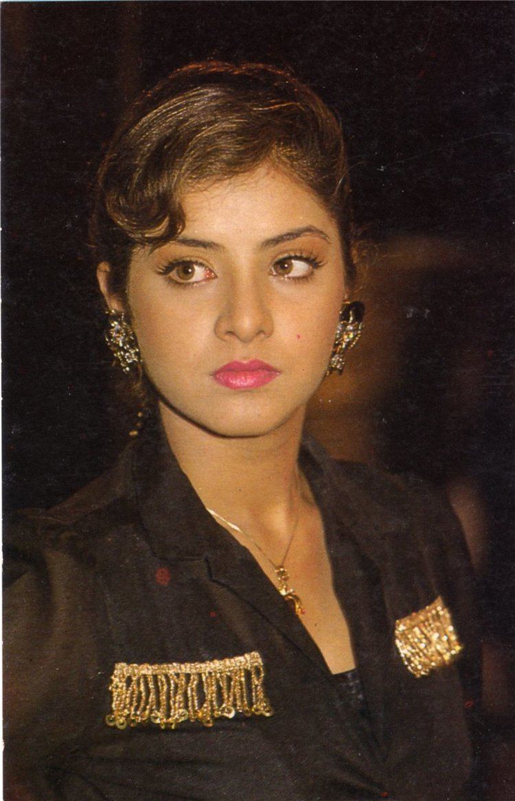 Divya Bharti wearing earrings, a necklace, and a black top.