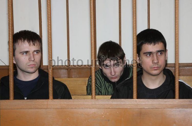 "​The Dnepropetrovsk Maniacs" inside the cell which Igor Suprunyuk wearing a black jacket and blue shirt, Alexander Hanzha wearing a green striped shirt, and Viktor Sayenko wearing a black jacket and shirt.
