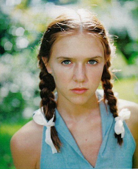 Young Dominique Swain as Lolita with a serious face, a braided hair with white ribbon, and wearing a blue halter top in a movie scene from Lolita, a 1997 romance drama film.