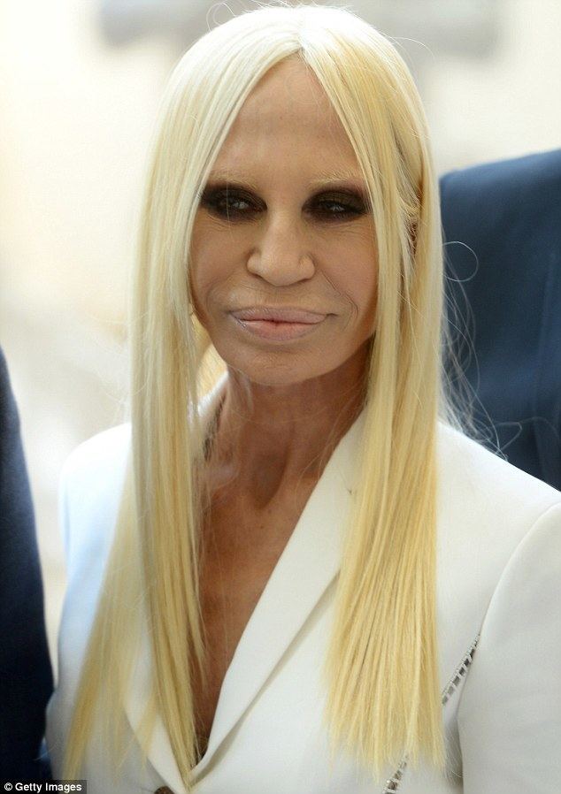 Donatella Versace smiling with a blonde hair and wearing a white coat