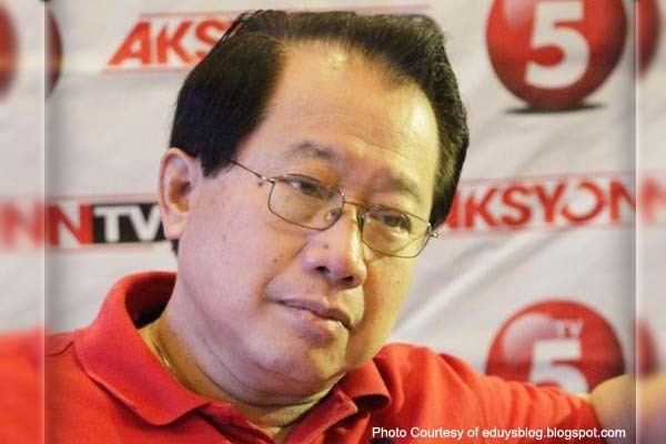 Dong Puno with a serious face, wearing eyeglasses and a red polo shirt.