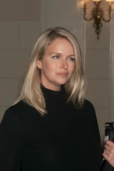 Donna Dixon smiling with blonde hair while wearing a black sweater