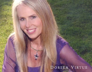 Doreen Virtue smiling while wearing a violet long sleeve blouse and necklace