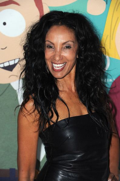 Downtown Julie Brown with a smile on her face, with curly black hair, and wearing a black tube dress.