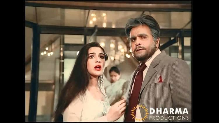 Amrita Singh (left) wearing a white dress and Dilip Kumar (right) wearing a suit and a tie in a movie scene from Duniya (1984 film).