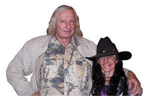 Durk Pearson smiling and wearing a gray and yellow long sleeve while Sandy Shaw also smiling and wearing a black hat