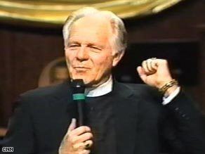 Earl Paulk holding a microphone with his clenched fist during his talk