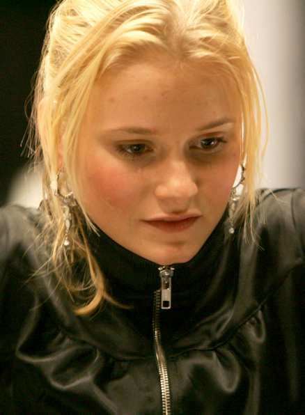 Ebba Hultkvist with a sad face, with pony-tailed blonde hair, wearing earrings and black jacket.