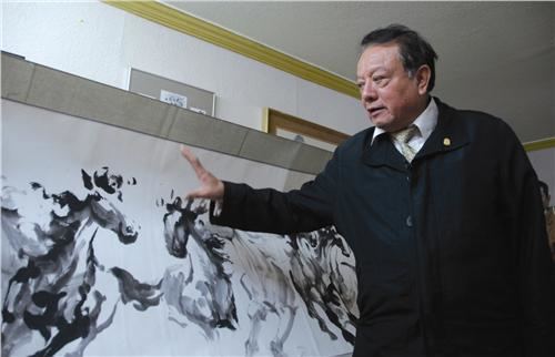 Eduardo Auyón with a painting of horses
