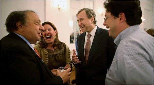 Edward F. Cox laughing with his friends while wearing black coat, white long sleeves and brown neck tie