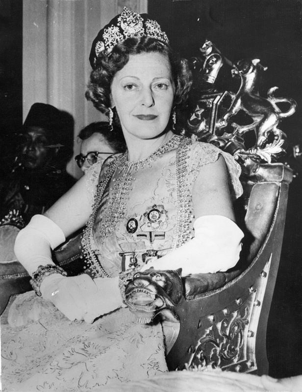 Edwina Mountbatten, Countess Mountbatten of Burma smiling while sitting on the chair and wearing a crown, gown, and gloves