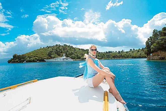 Ekaterina Rybolovleva at Skorpios Island wearing scarf, shades, blue top and white shorts
