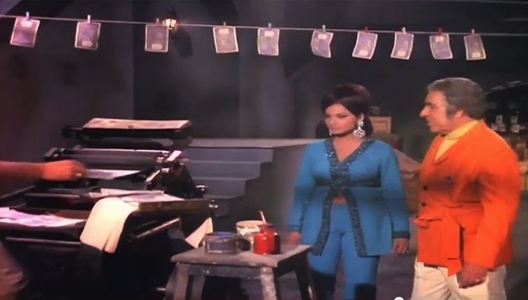 Rekha wearing a blue long sleeve blouse while Madan Puri wearing a red coat in a scene from the 1971 Bollywood Sci-Fi thriller film, Elaan