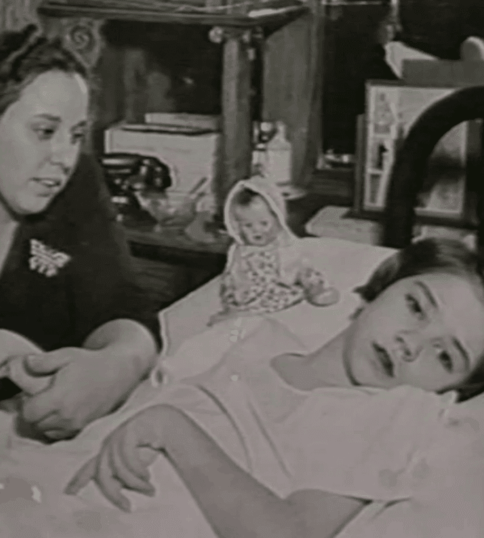 Elaine Esposito lying on a bed while her mom Lucy Esposito holding her hand