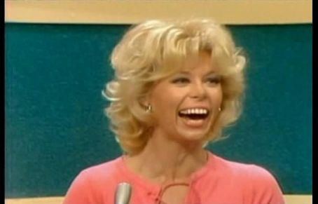 Elaine Joyce laughing during the Match Game Comedy's game show while wearing a peach blouse and earrings