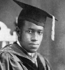 Elbert Frank with a serious face and wearing a graduation hat and gown.