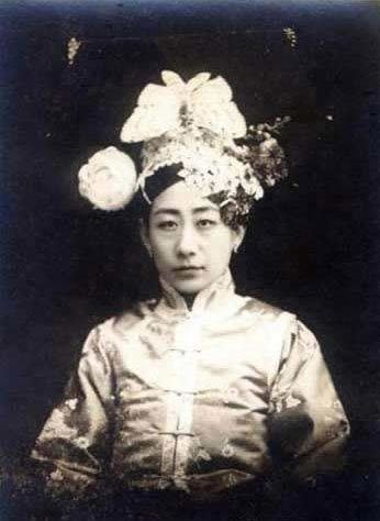 Jin Moyu with a serious face, wearing a headdress, and a qipao dress.