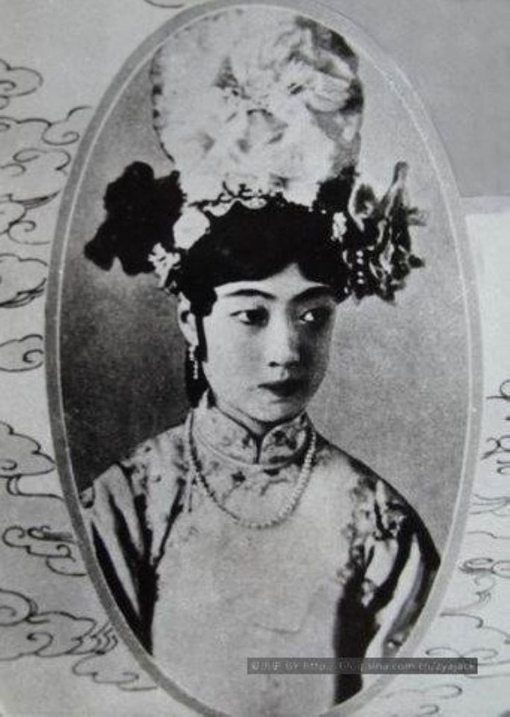 Empress Wanrong with a serious face, wearing a headdress, a necklace, and a qipao dress.