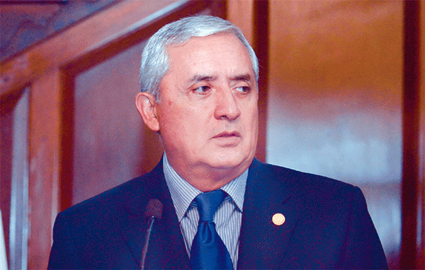 Enrique Molina Sobrino having a microphone in front while wearing a blue shirt, a tie, and a coat
