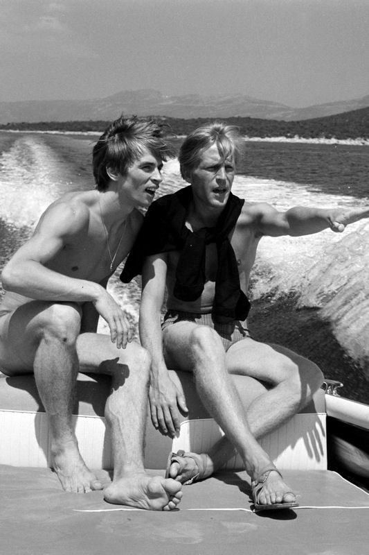 Erik Bruhn riding a boat with Rudolf Nureyev out at sea and wearing beach shorts.