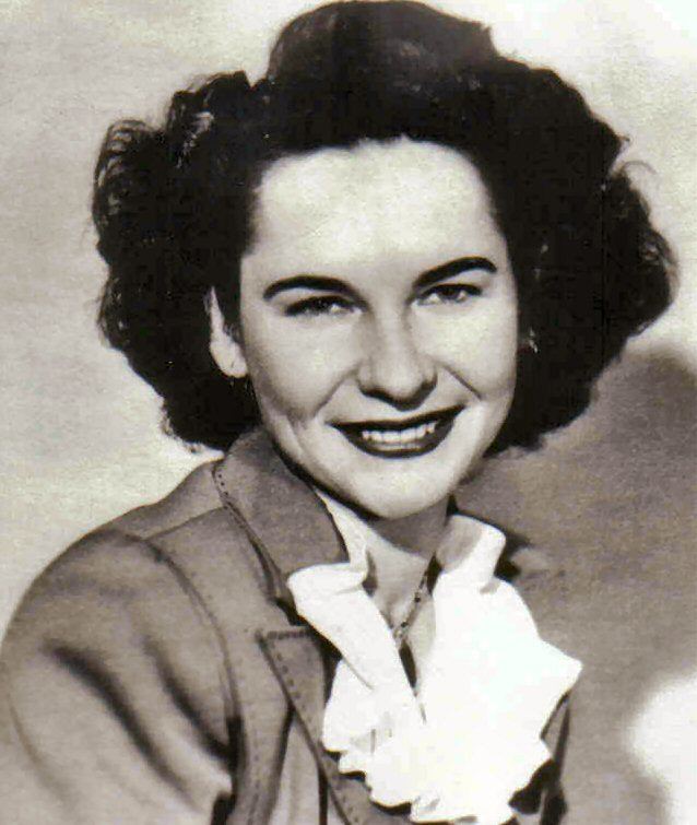 Ernestine Wiedenbach with a smiling face, curly short hair, and wearing a necklace.