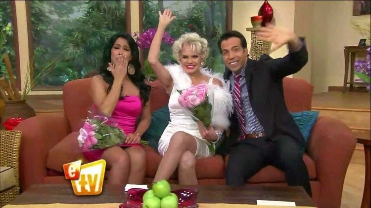 Marisa del Portillo, Charytín Goyco, and Felipe Viel hosting the Escándalo TV show while waving their hands as they sit on the orange couch