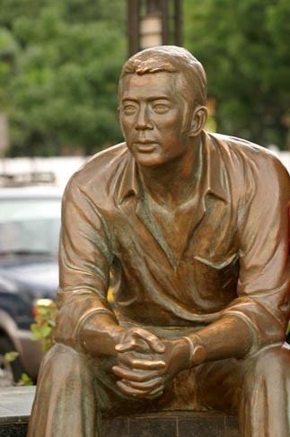 Bronze statue of Evelio B. Javier in a sitting position while holding both hands together with fingers crossed located at Manila Baywalk, Philippines.
