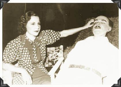 Evelyn Frechette sitting beside the wax figure of John Dillinger while wearing a blouse with puff sleeves