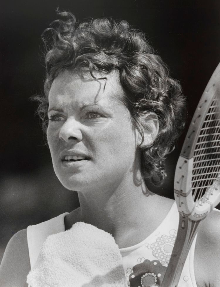 Evonne Goolagong Cawley with curly hair and holding a racket