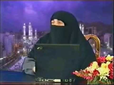 Farhat Hashmi with a laptop on the table and with a bouquet of flowers, wearing a gray thobe and a black Shemagh.