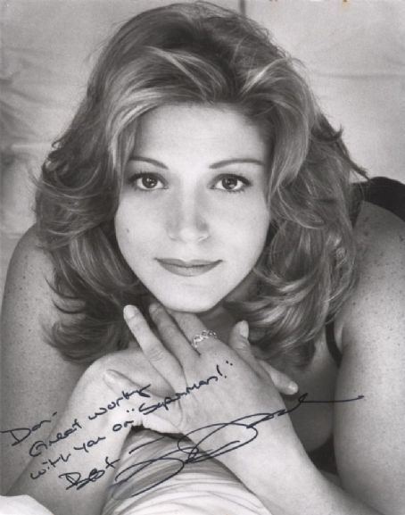 Farrah Forke with a tight-lipped smile and curly hair while her hands together showing her ring and an autograph on the lower left part