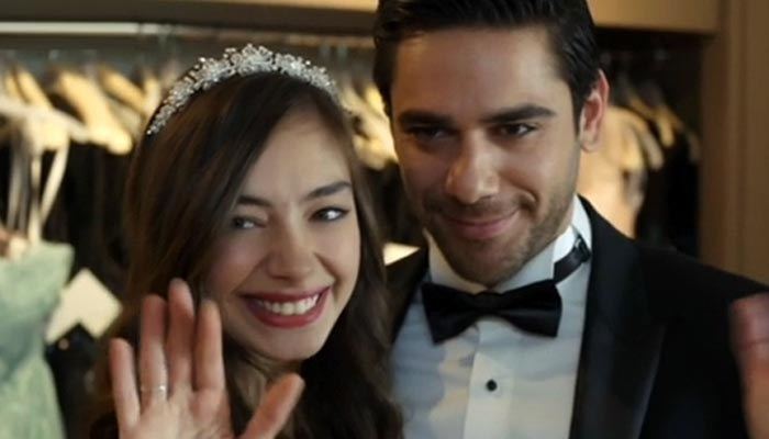 Neslihan Atagül smiling with Kadir Dogulu wearing a black coat, white long sleeves, and bow tie