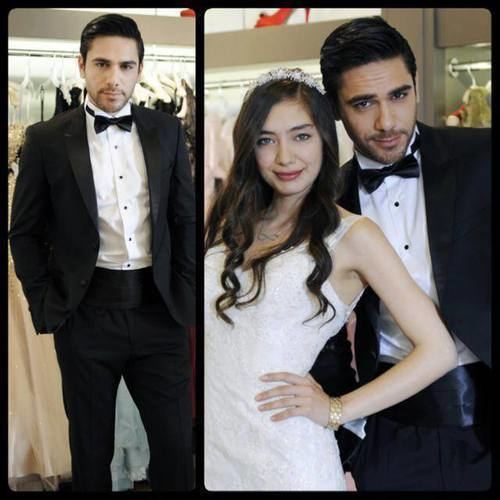 Neslihan Atagül smiling and wearing a white dress while Kadir Dogulu wearing a black coat, white long sleeves, and bow tie