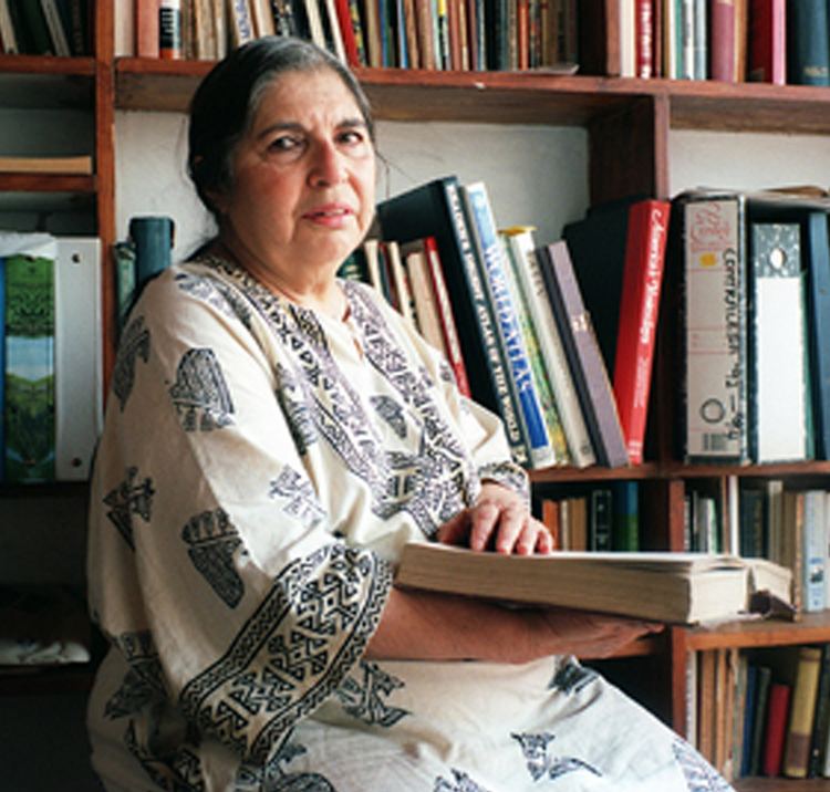 Fatima Meer sitting while holding a book and wearing a white with black dress