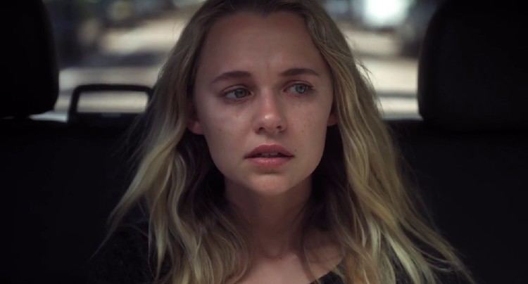 Madison Iseman riding in a car and looking terrified with her blonde hair down in a scene from the 2021 movie "Fear of Rain"